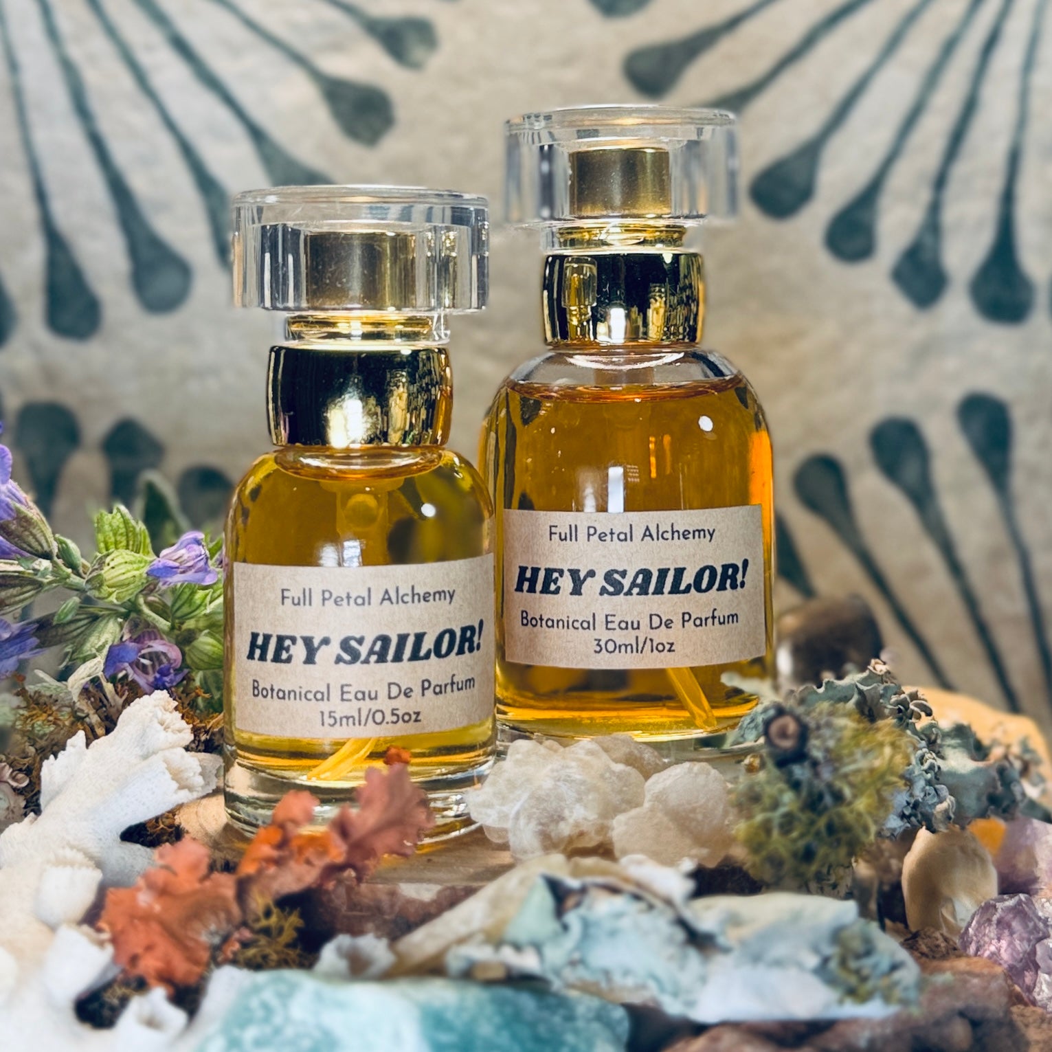 Two bottles of 'Hey Sailor!' botanical eau de parfum on a decorative background with seashells and flowers.