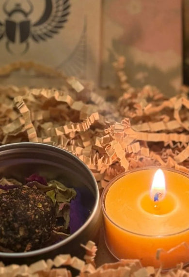 Candle and small container on crinkled paper with 'The Ritual of Kail' book in the background.