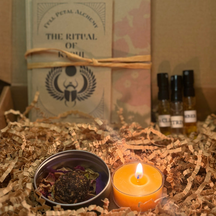 Candle and small container on crinkled paper with 'The Ritual of Kail' book in the background.
