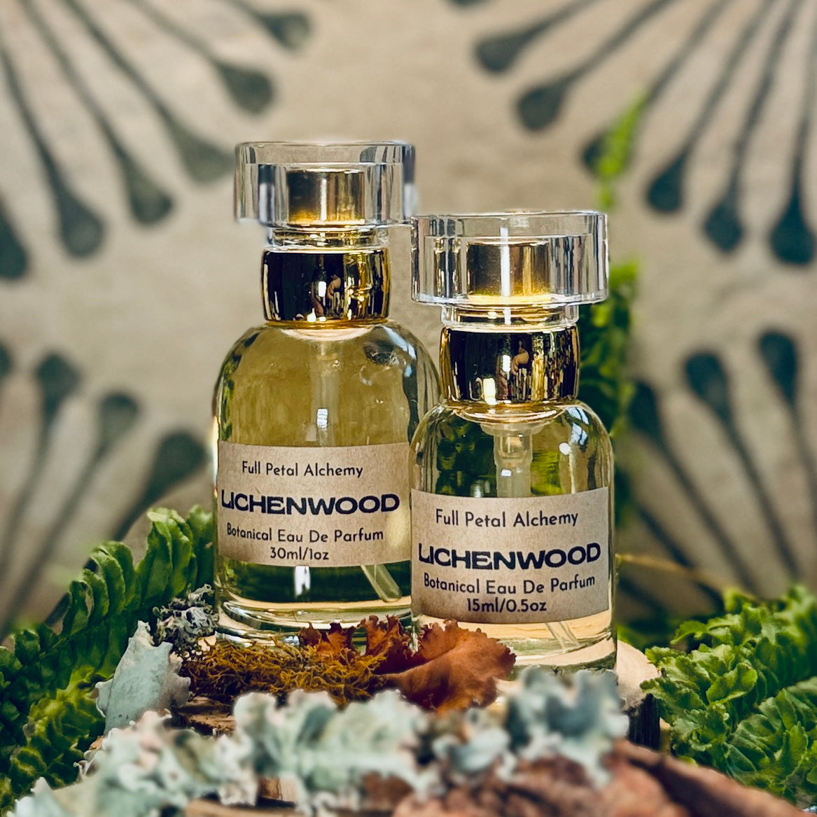 Two bottles of Full Petal Alchemy Lichenwood botanical eau de parfum on a natural background with leaves.