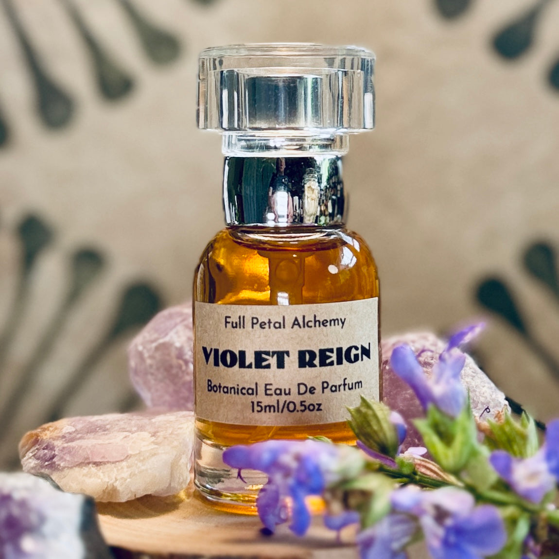 Violet Reign 15ml botanical eau de parfum bottle with flowers and crystals on a wooden surface.